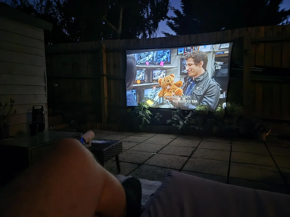 Amazon customer photo showing a TURN1-style projector used outdoors after sunset